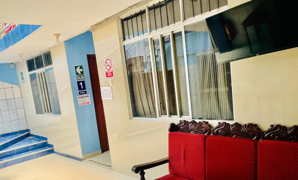 Hotel Juan Diego Pucallpa في بوكالبا: غرفة انتظار مع كرسي احمر امام مبنى