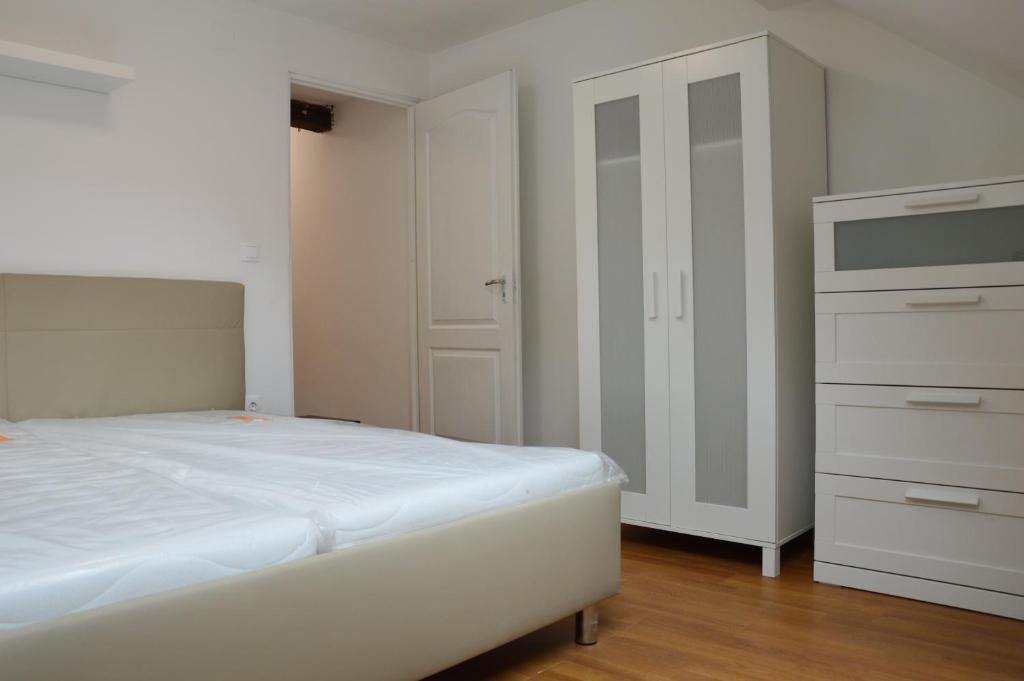 a bedroom with a white bed and a dresser at Haus Im Zentrum M - 3 Schlafzimmer Wohnung in Szombathely