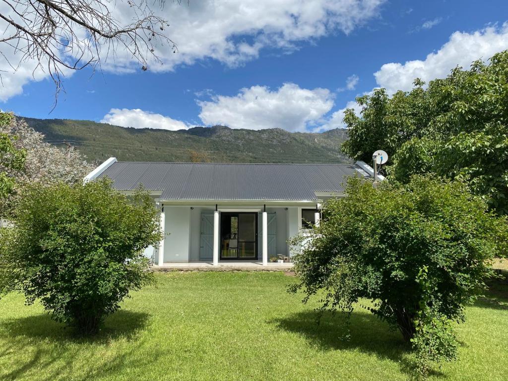 a white house with two bushes in a yard at Kalimera in Lago Puelo