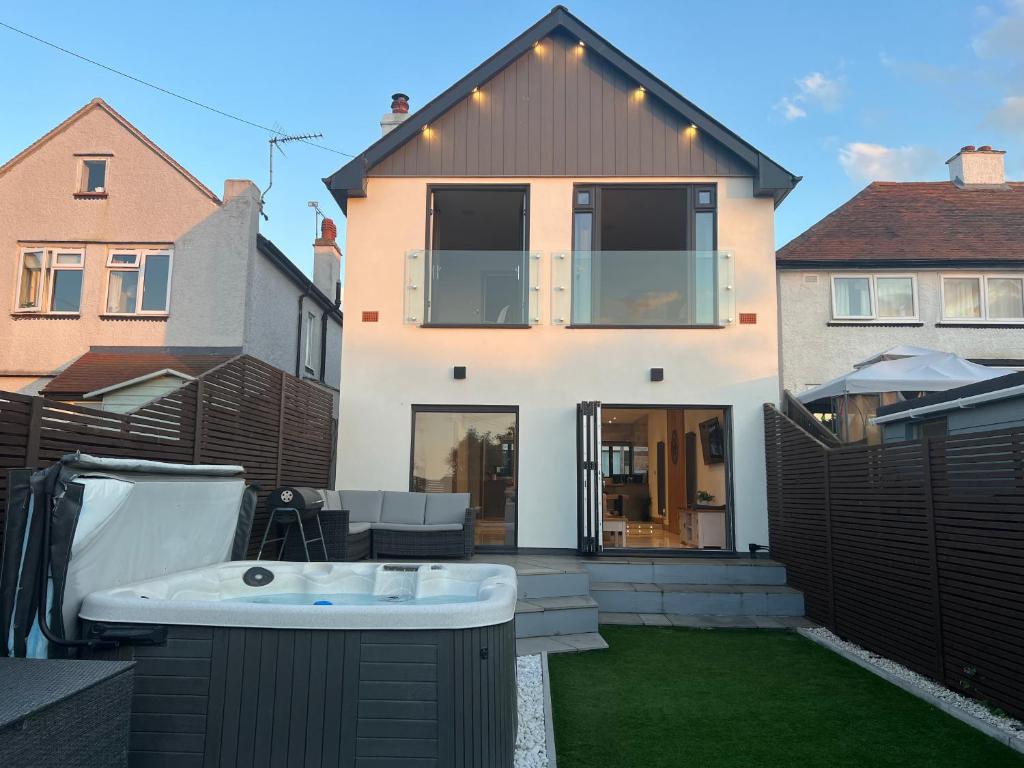 un patio trasero con bañera de hidromasaje y una casa en Broadway Beach Home with Hot tub en Herne Bay