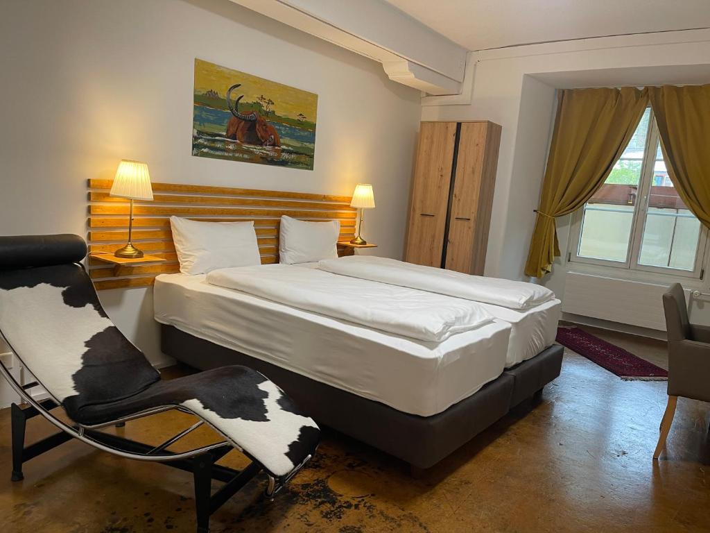 a bedroom with a large bed and a chair at Hotel Swiss Bellevue Aathal in Seegräben