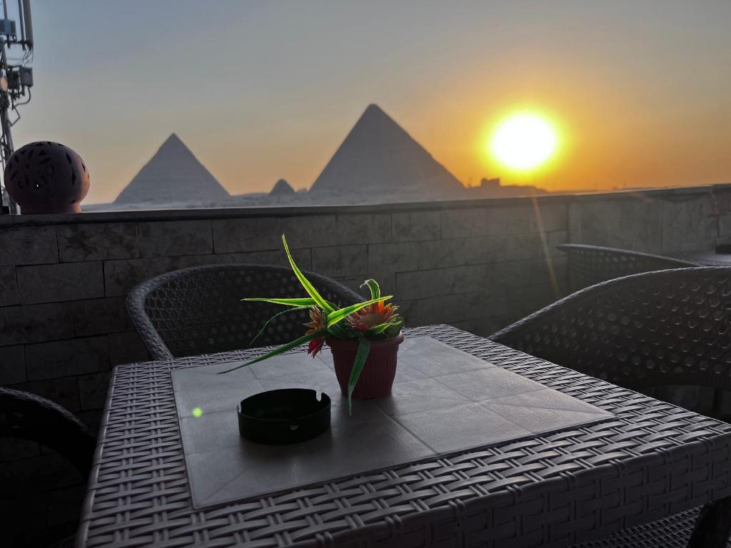 een tafel met een plant op een balkon met een zonsondergang bij Aton pyramids INN in Caïro