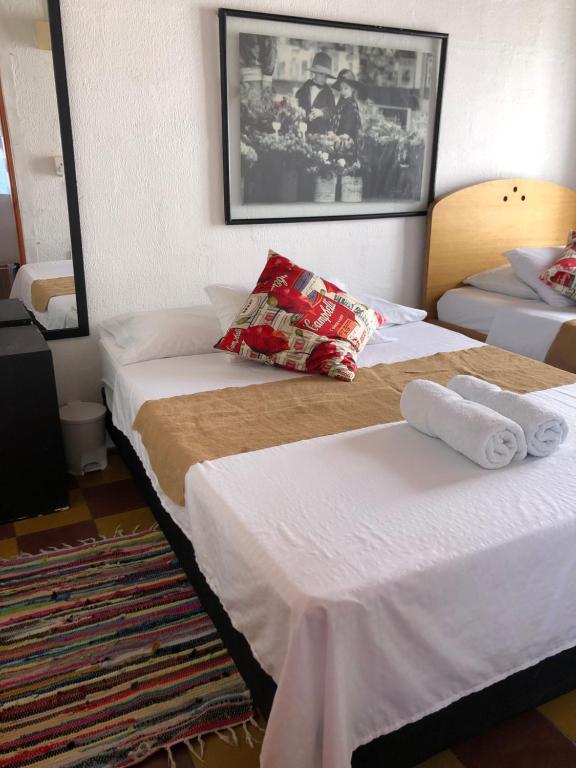 Dos camas en una habitación de hotel con toallas. en apartasuite Centro Historico en Santa Fe de Antioquia