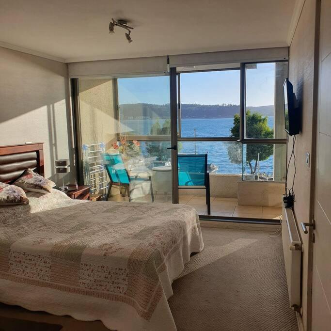 a bedroom with a bed and a view of the ocean at Departamento en Condominio privado Costa Pingueral in Concepción