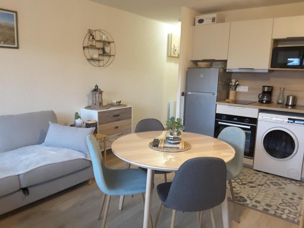 a kitchen and a living room with a table and chairs at Studio 24 m2 - 4 personnes in Besse-et-Saint-Anastaise