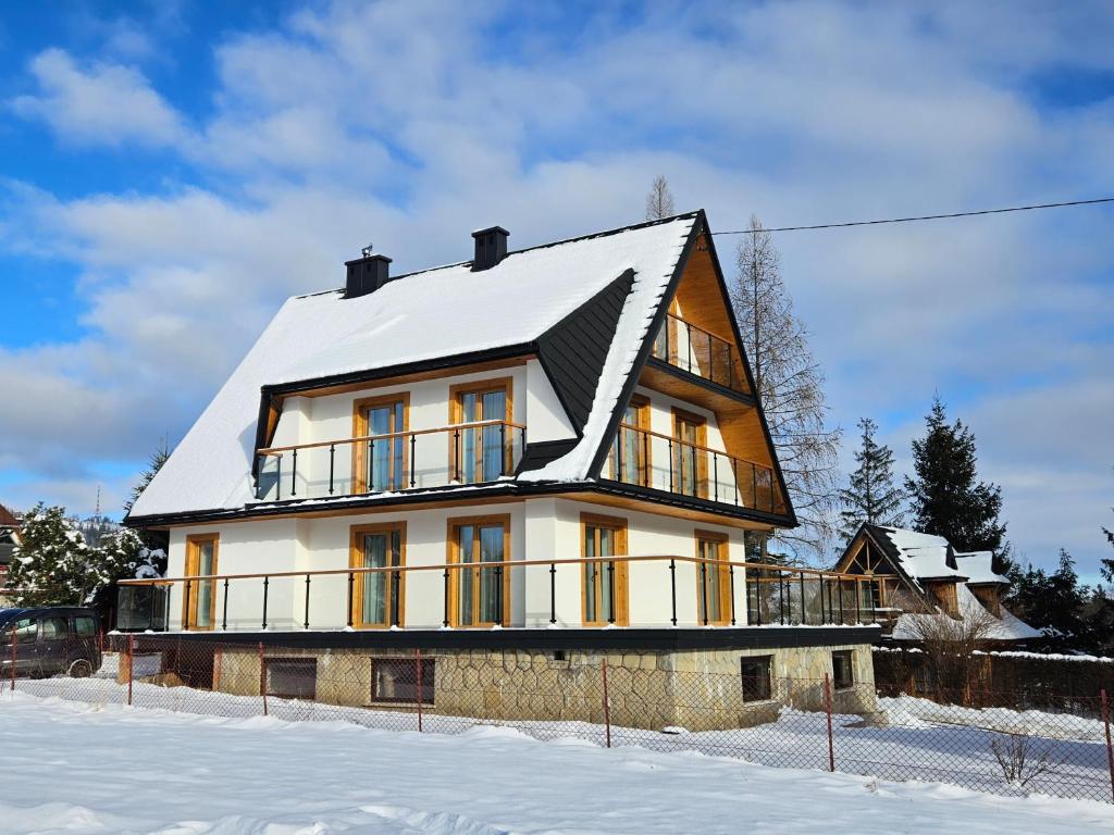 a house with a snow covered roof in the snow at Willa Szyszka Zakopane in Zakopane