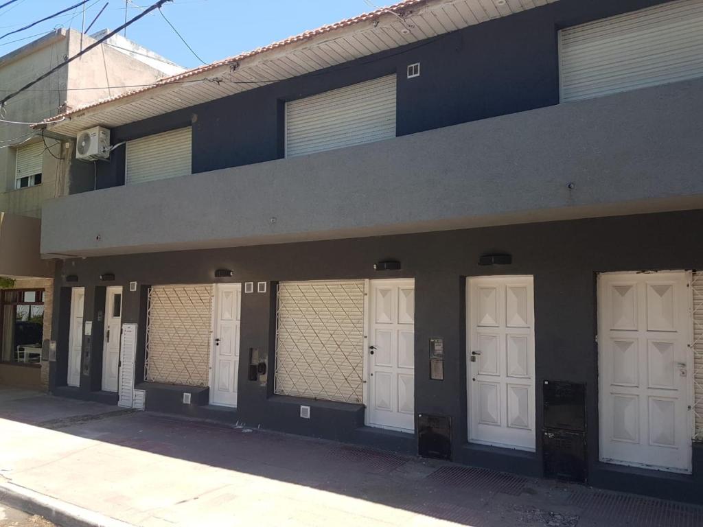 una fila de cuatro puertas blancas en un edificio en Departamentos calle 8 en Necochea