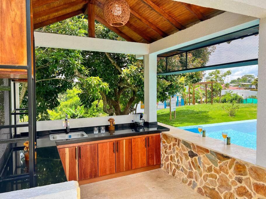an outdoor kitchen with a view of a swimming pool at Finca Villa Sophia! in Quimbaya