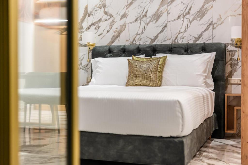 1 dormitorio con 1 cama con sábanas blancas y almohadas de oro en Royal Gold City Suites by Estia en Heraclión