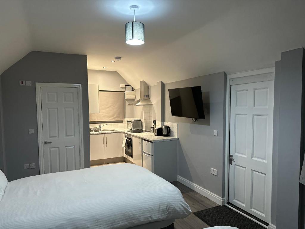 a bedroom with a white bed and a kitchen at Ruxley Studios in Orpington
