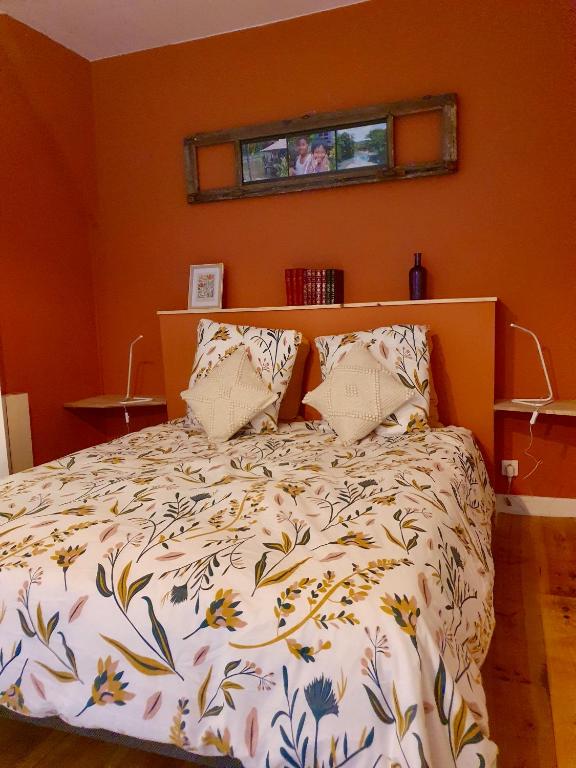 a bed in a bedroom with an orange wall at Chambres d&#39;Hôtes du Domaine de Bourbacoup in Tulle