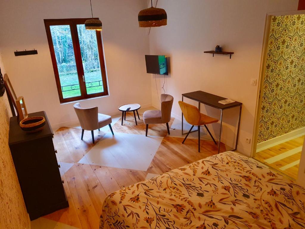 a bedroom with a bed and a desk and chairs at Chambres d&#39;Hôtes du Domaine de Bourbacoup in Tulle