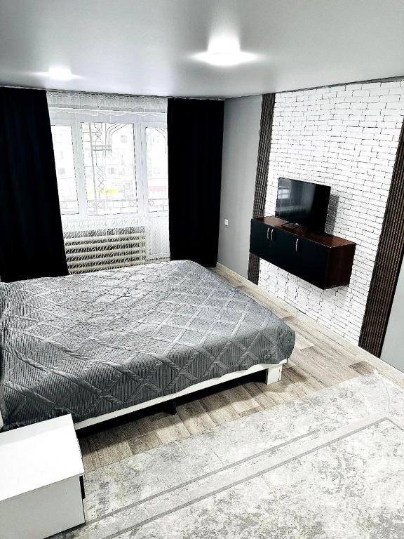 um quarto com uma cama e uma televisão de ecrã plano em Независимости 5а em Sätbaev