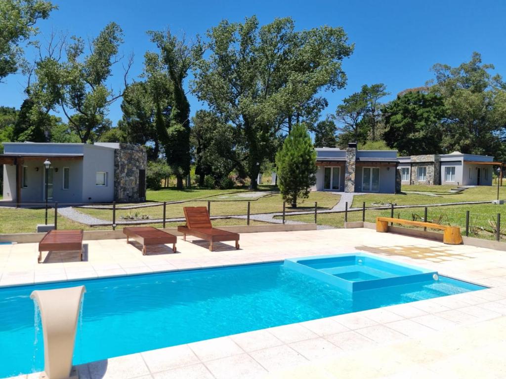 una piscina con sillas y una casa en Cabañas El Rincon en Tandil