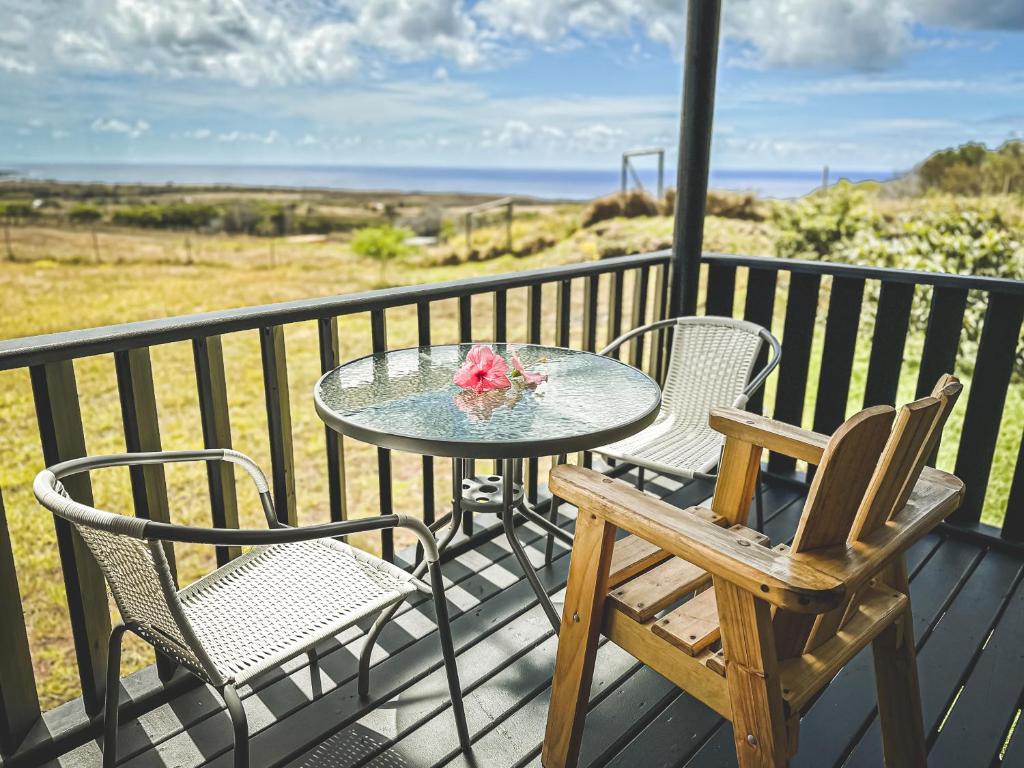 een tafel en stoelen op een balkon met uitzicht op de oceaan bij Maunga Roa Eco Lodge in Hanga Roa
