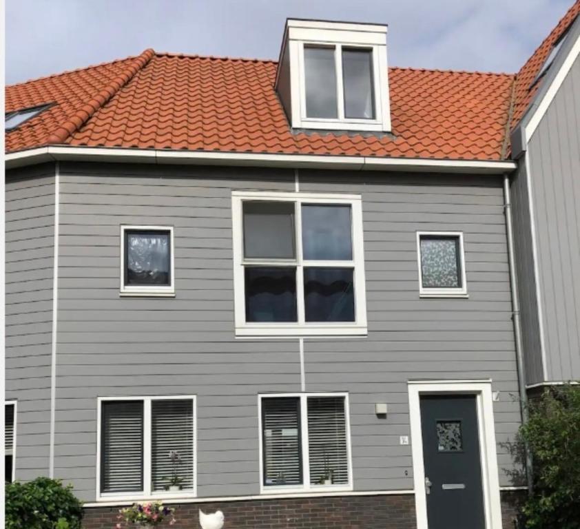una casa gris con techo naranja en B&B Twiske Zuid, Amsterdam free parking, en Ámsterdam