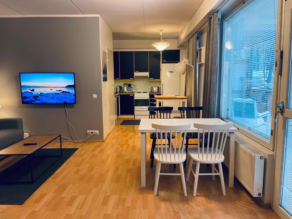 a kitchen and living room with a table and chairs at Hotel-standard design apartment with private sauna and terrace in Espoo