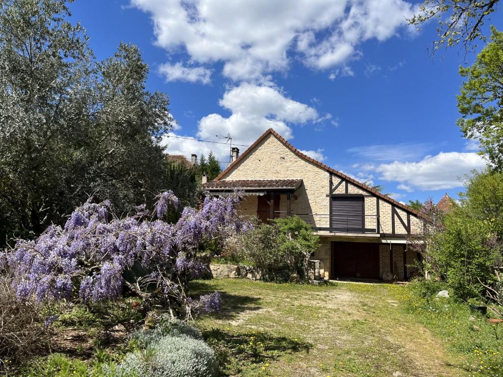 une maison avec des fleurs violettes devant elle dans l'établissement Aux Mille et Une Etoiles, gite a la campagne, à Saint-Martin-Labouval