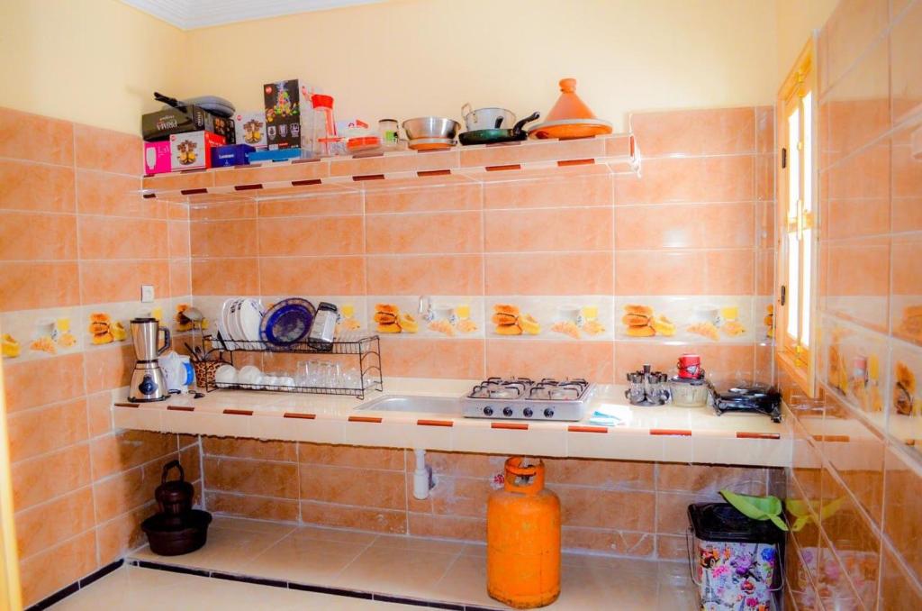 eine geflieste Küche mit einem Waschbecken und einigen Regalen in der Unterkunft Maison sahara in Ad-Dakhla