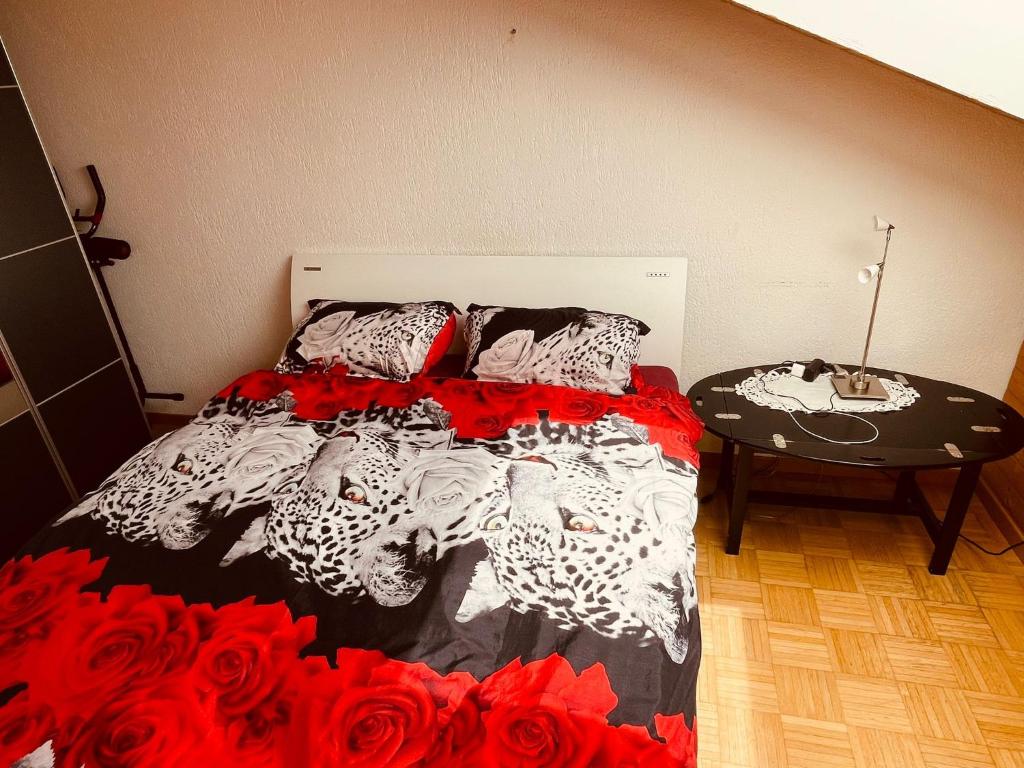 a bed with a black and white comforter and a table at Sehr gemütliches und gepflegtes Zimmer 8 Km von Bern-City in Köniz