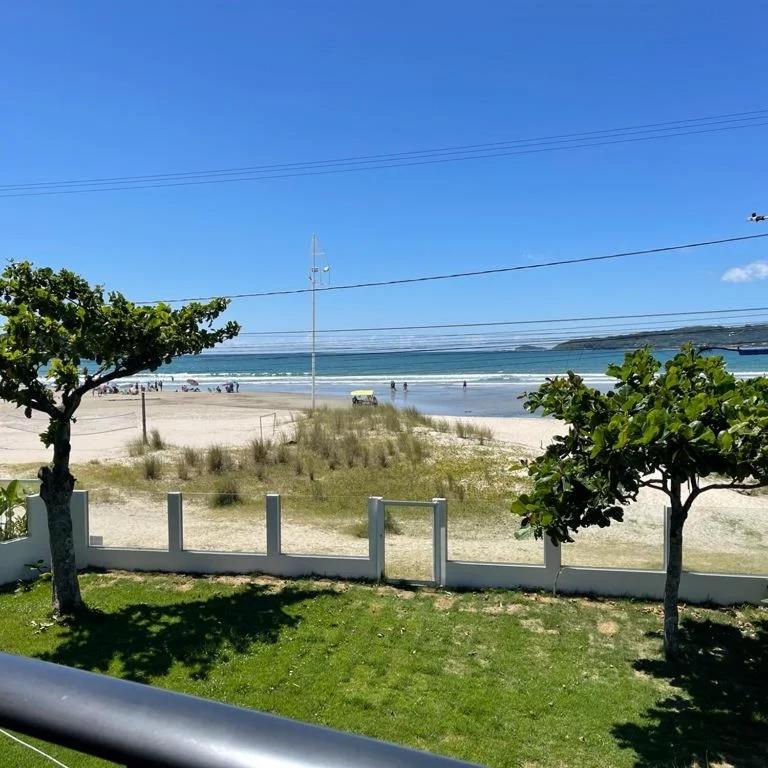 a view of a beach with a fence and two trees at ponta do papagaio in Palhoça