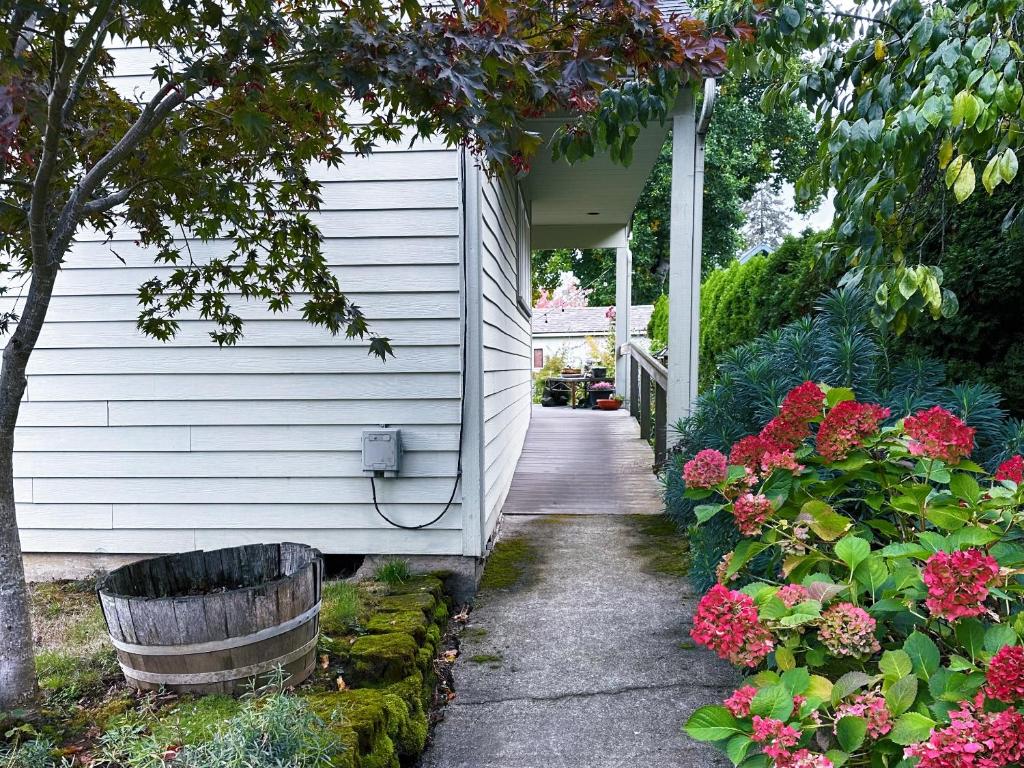 una pasarela que conduce a una casa blanca con flores en The Secret Garden en Portland