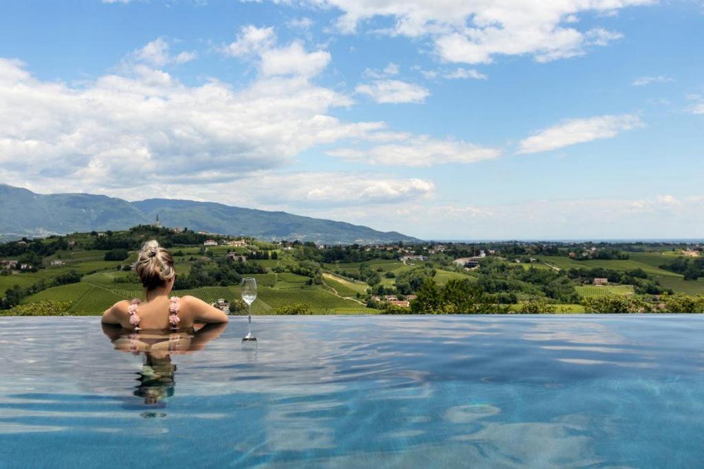 une femme dans l'eau d'une piscine dans l'établissement Villa del Poggio Prosecco Bike Hotel, à San Pietro di Feletto