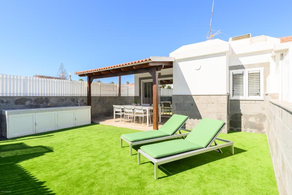 ein Hinterhof mit grünem Rasen und zwei Liegestühlen in der Unterkunft Beachside hideaway Gran Canaria in San Bartolomé de Tirajana