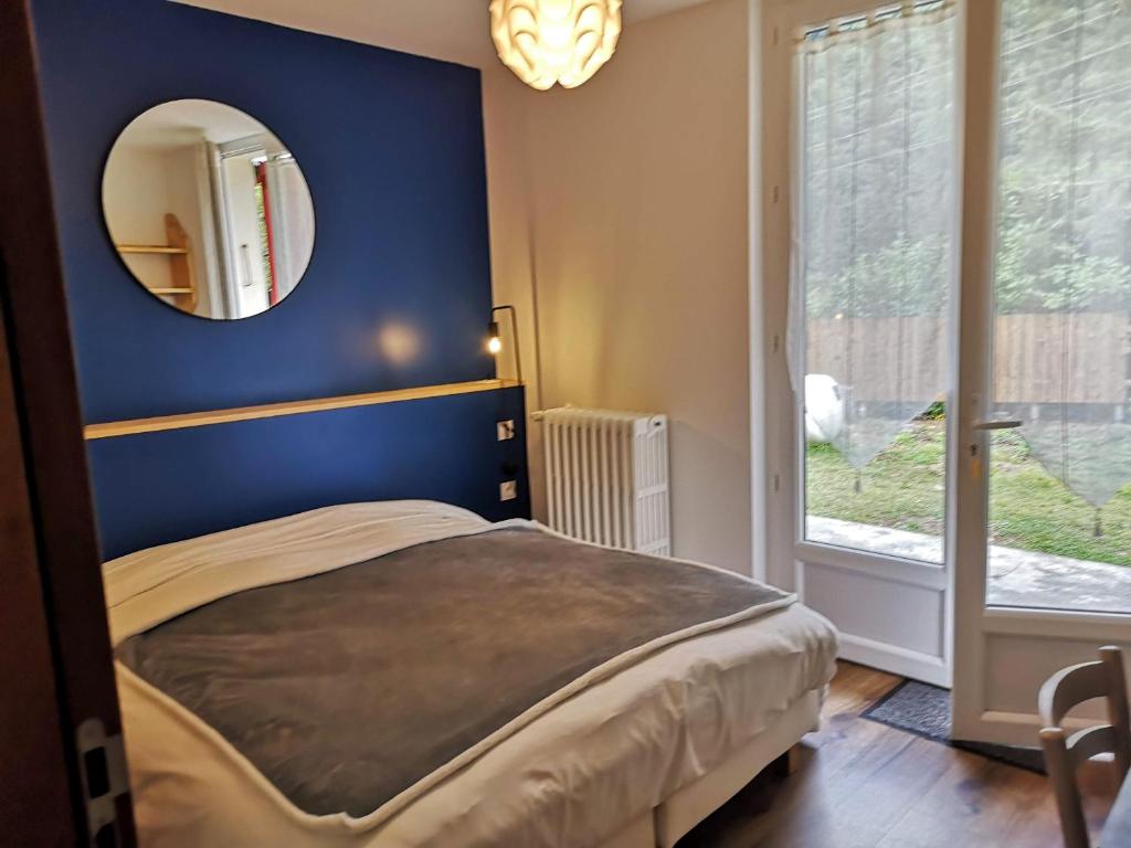1 dormitorio con pared azul y espejo en Le Relais d'Avajan en Avajan