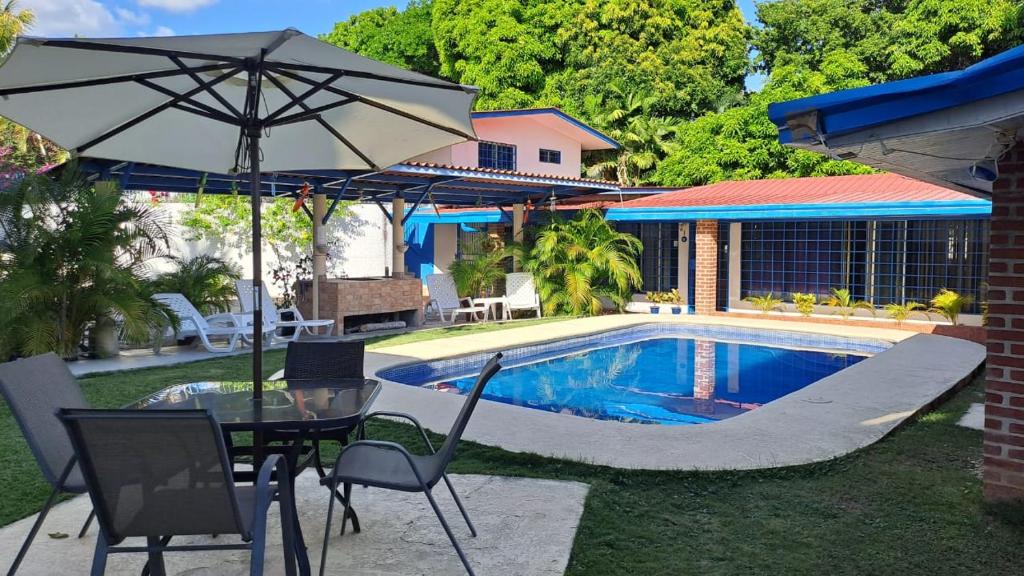 a patio with a table and an umbrella next to a pool at Hostal Villa Mayte Coronado in Las Lajas