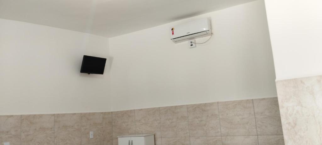 a room with a tv on the ceiling with a wall at Pousada do Gilmar in Ribeirão
