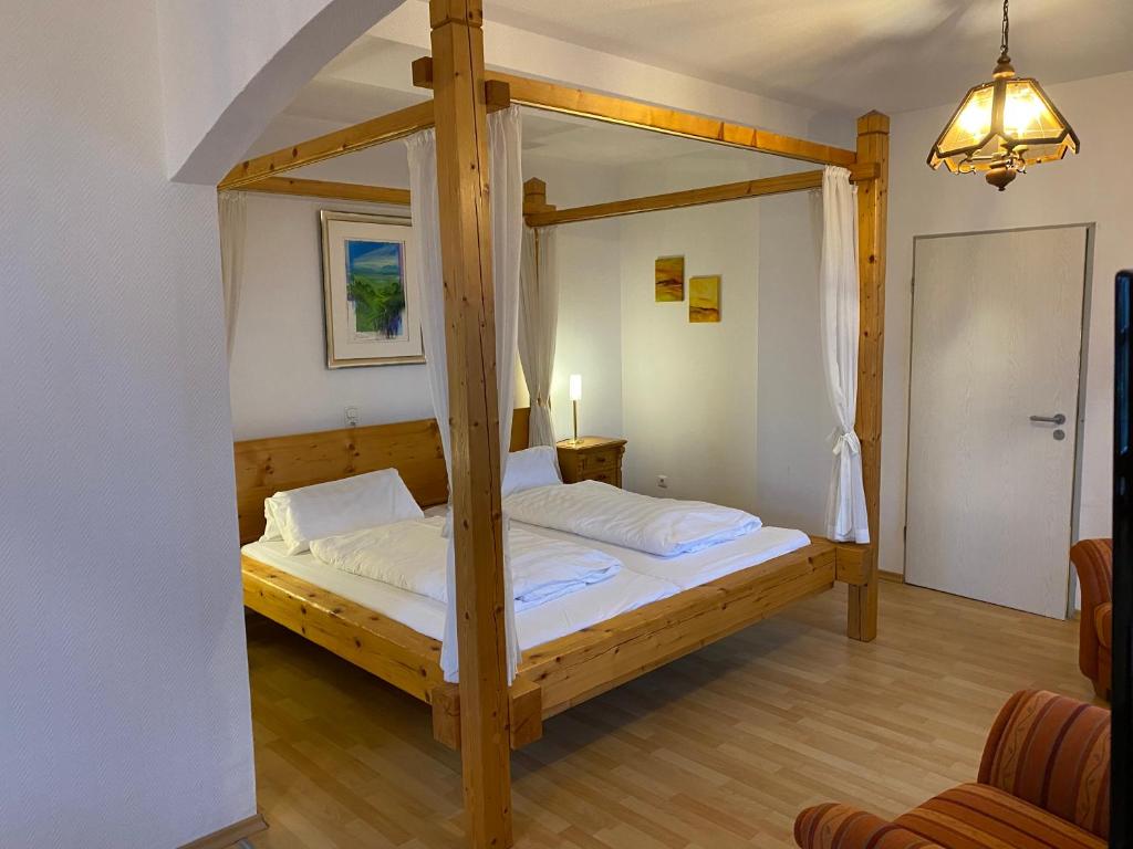 Schlafzimmer mit einem Himmelbett aus Holz in der Unterkunft Schlossschänke Friedenfels in Friedenfels