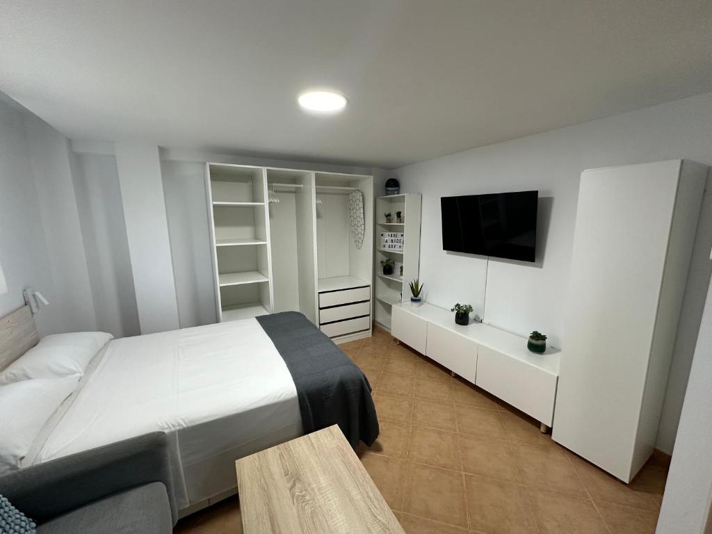 a bedroom with a white bed and a television at Apartamento Avenida Velazquez Planta Baja in Málaga