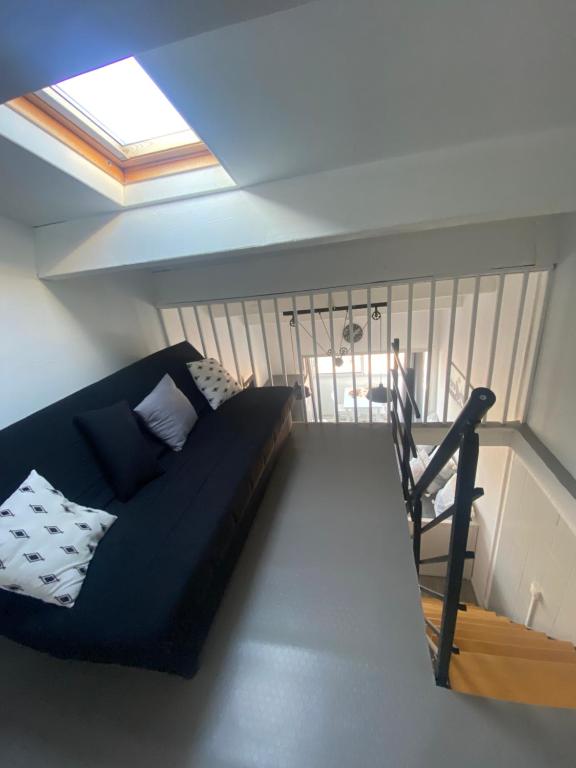 Una sala de estar con un sofá negro y una ventana. en T3 Cosy et Confortable à deux pas des Plages, en Sète