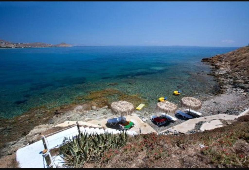 grupa parasoli i leżaków na plaży w obiekcie Agali bay hotel w mieście Tinos