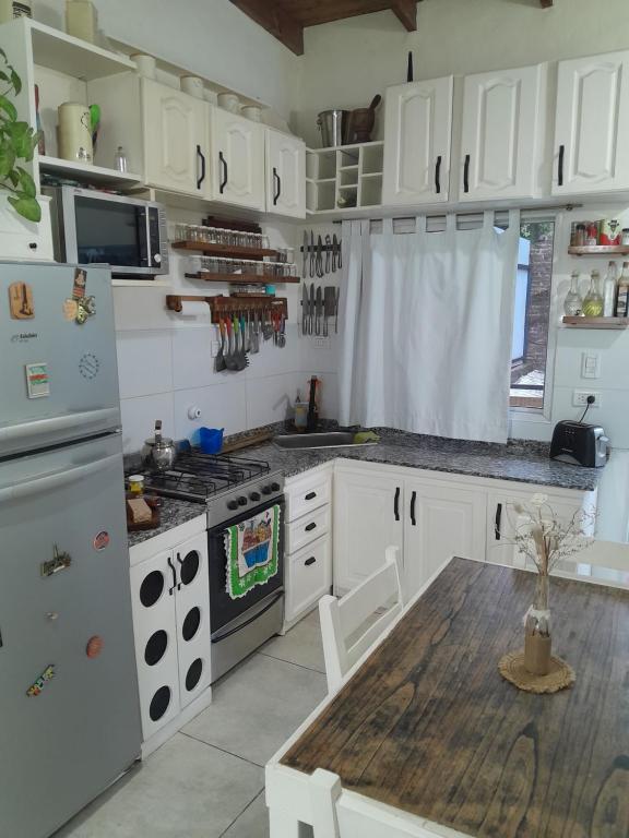 cocina con armarios blancos y mesa de madera en La casita de Tigre Centro en Tigre