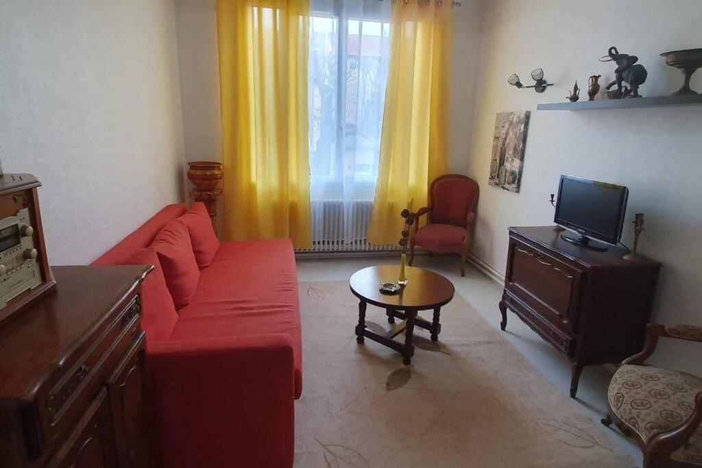 a living room with a red couch and a television at Grand appartement proche Paris in Montreuil