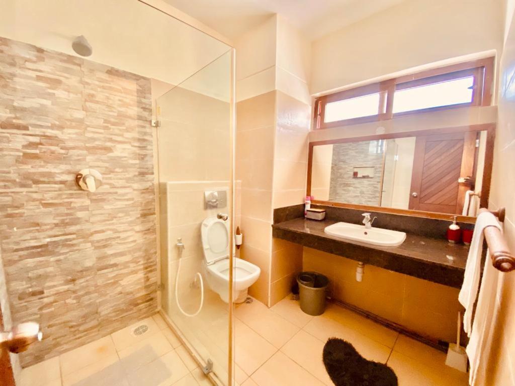 een badkamer met een douche, een toilet en een wastafel bij Sophlin home in Ukunda