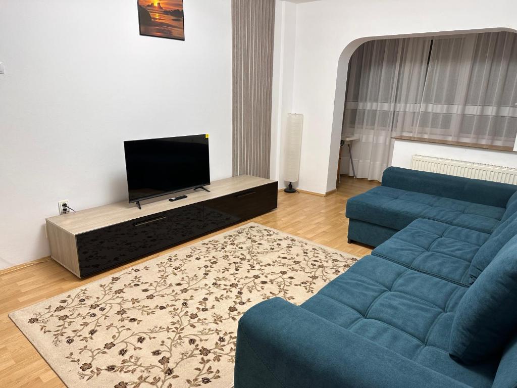 un soggiorno con divano blu e TV a schermo piatto di UrbanEscape a Onești