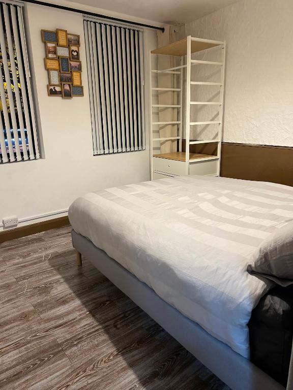 een slaapkamer met een bed en een boekenplank bij 2 bedroom flat in Swansea