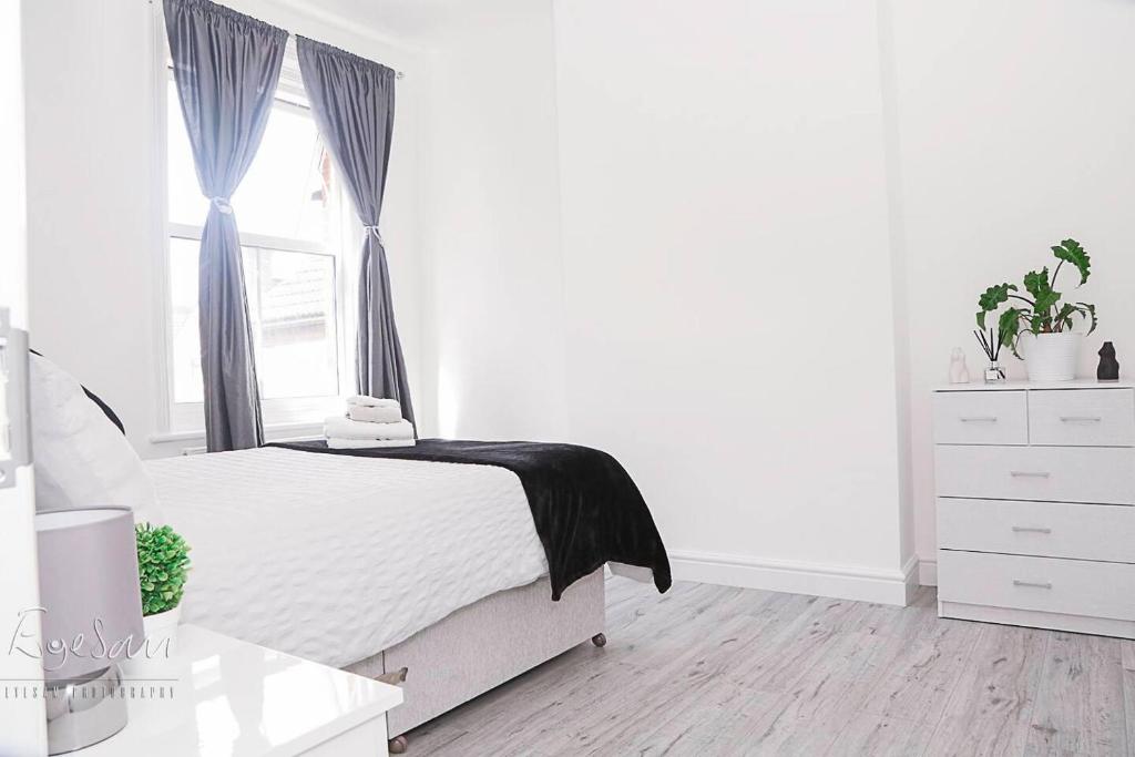 um quarto branco com uma cama e uma janela em Inviting 3-Bed Apartment in Bromley em Bromley