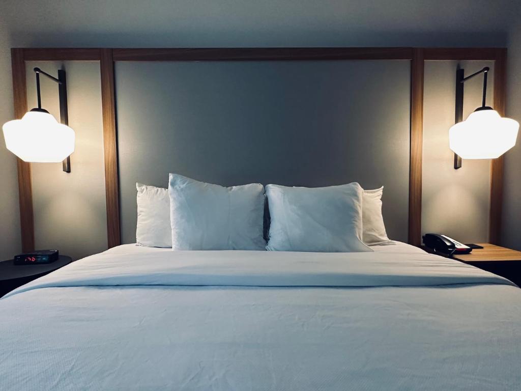 a bedroom with a bed with white pillows and two lights at Hotel Scottsdale in Scottsdale
