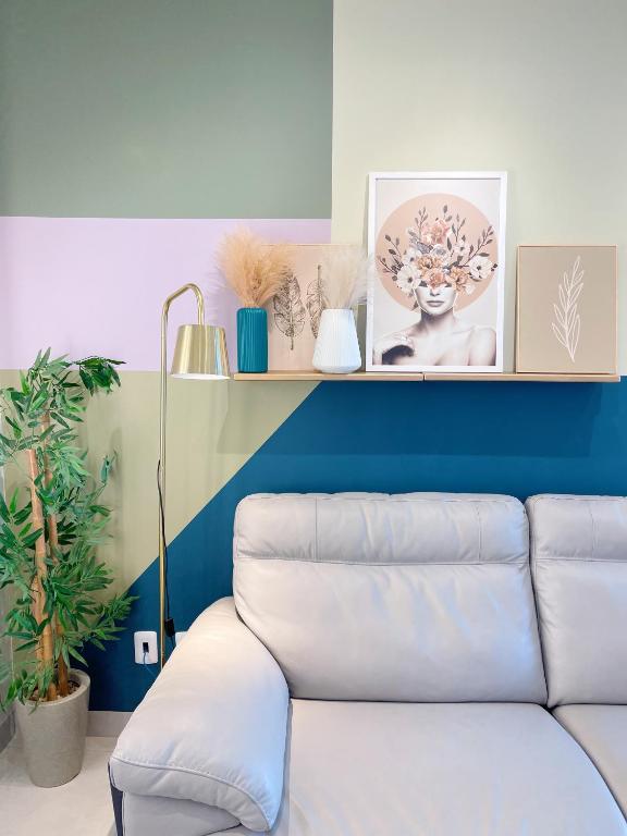 a living room with a white couch and a blue wall at PALMAS EXPERIENCE - Apartamento Girassol in Palmas