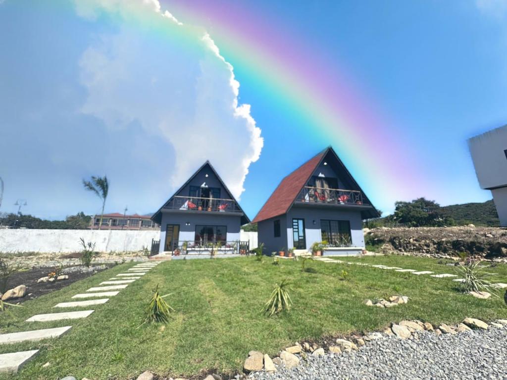 two houses with a rainbow in the sky at Piece Of Heaven Cabins in Palmira