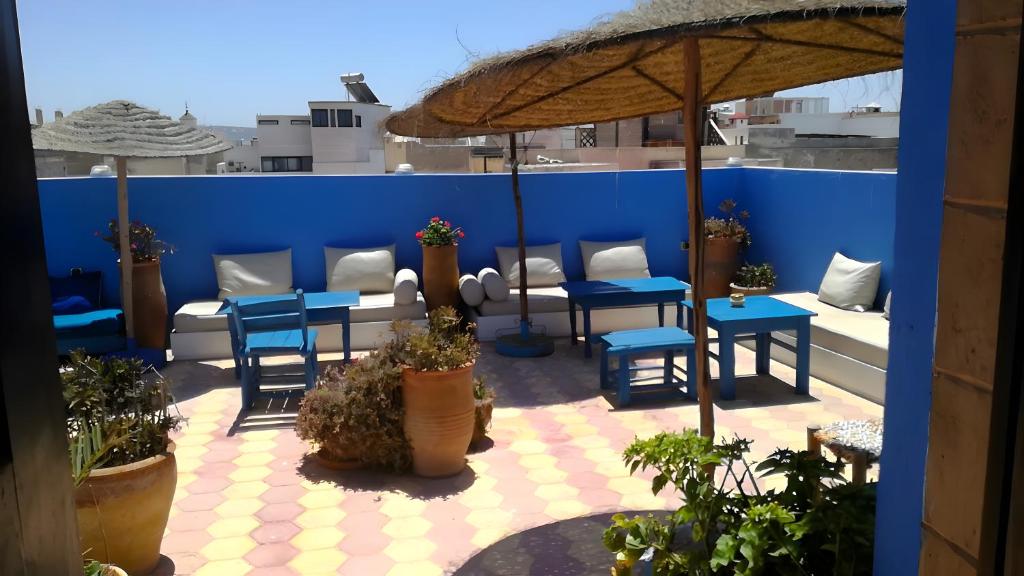 a patio with blue tables and chairs and an umbrella at Riad Le Grand Large in Essaouira