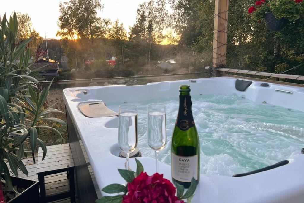 a bottle of wine and glasses in a hot tub at Charmig liten stuga i Södertälje/ Kungsdalen in Södertälje