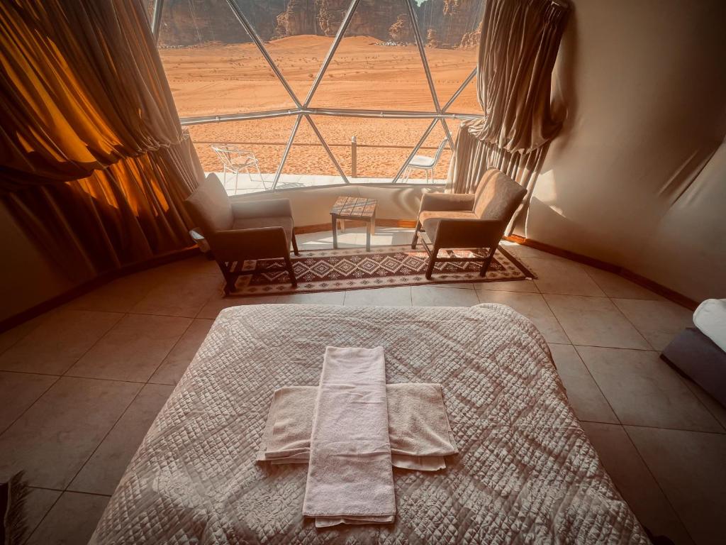 a bed in a room with a large window at RUM ROYAL FLOWER lUXURY CAMP in Wadi Rum