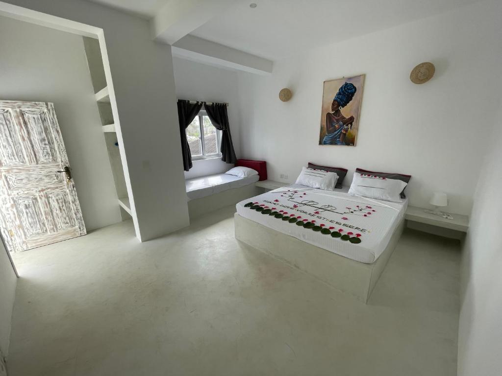 a white bedroom with a bed and a window at Ascot Watamu in Watamu