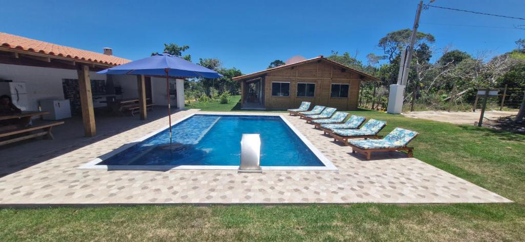 a swimming pool with lounge chairs and an umbrella at Solar das Bromélias in Arraial d'Ajuda