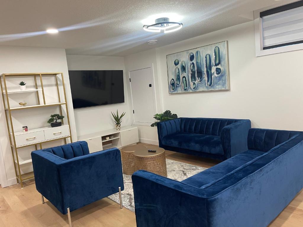 a living room with blue couches and a flat screen tv at Stylish 2 Bedroom suite in SW Edmonton close to Windermere and Edmonton International Airport in Edmonton